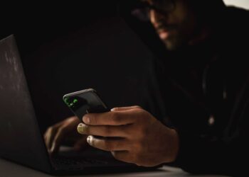 Photo by Sora Shimazaki: https://www.pexels.com/photo/crop-ethnic-hacker-with-smartphone-typing-on-laptop-in-dark-room-5935792/